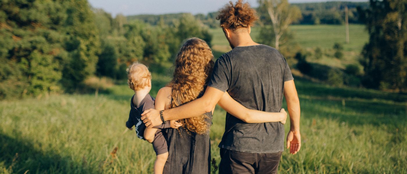 Родители с ребёнком идут по зелёному лугу
